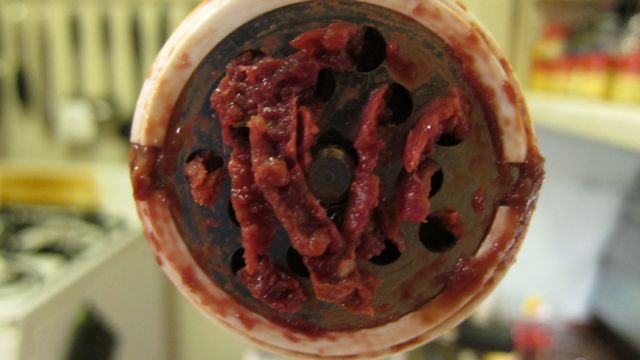 mangle meat grinding plate with meat oozing from it