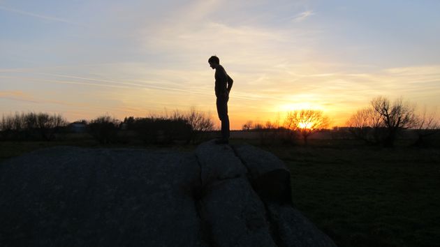 silhouetted man against the sunset on a glacier rock