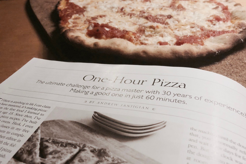Cookâ€™s Illustrated magazine alongside a pizza made from the recipe shown